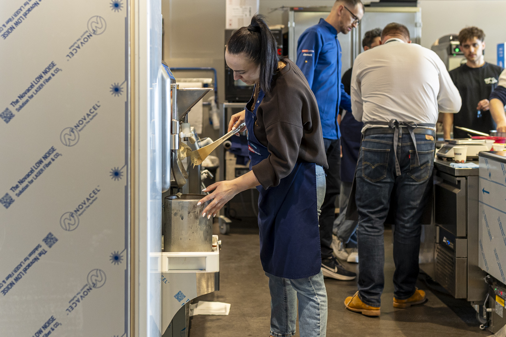 Uczestniczka szkolenia odbiera gotowy produkt bezpośrednio z frezera, poznając kluczowy etap produkcji lodów rzemieślniczych. Praktyczna prezentacja procesu zamrażania i tekstury lodów w profesjonalnych urządzeniach Carpigiani.