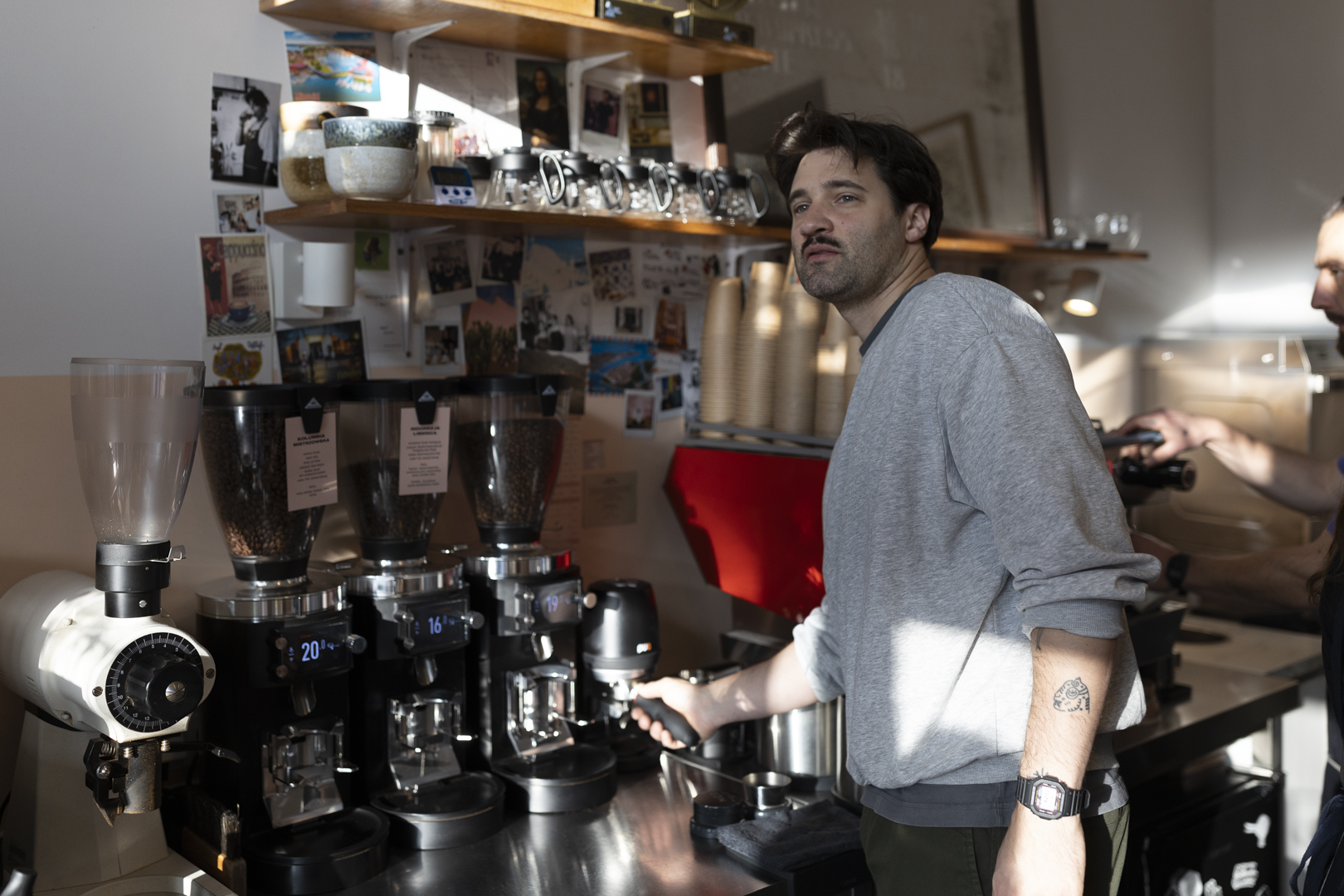 Michał Ciupiński, Mistrz Polski Barista oraz Coffee in Good Spirits, podczas pracy za barem w kawiarni Błysk. W tle widoczne profesjonalne młynki do kawy Mahlkönig, wykorzystywane w codziennej pracy oraz w procesie przygotowań do startów konkursowych.