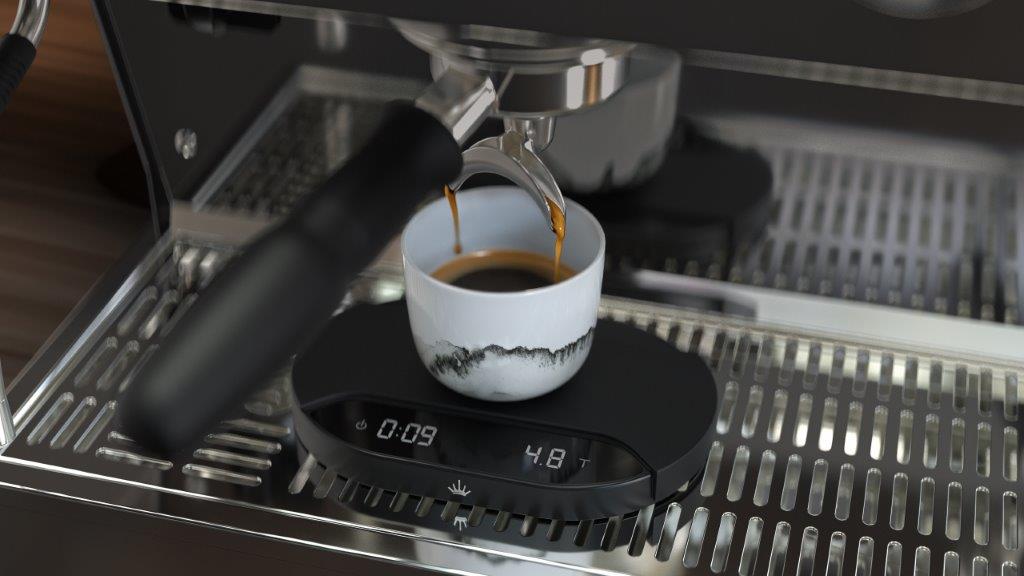 Inteligentna waga Mahlkönig Sync Scale mierzy czas i wagę ekstrakcji espresso, synchronizując dane z młynkiem Grind-by-Sync w ramach ekosystemu Mahlkönig Sync. Na zdjęciu filiżanka espresso ustawiona na wadze pod kolbą ekspres